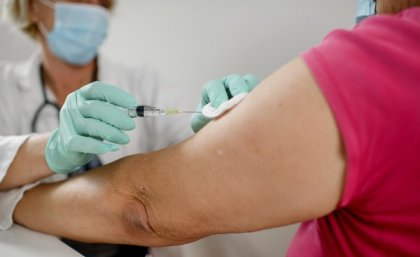 Vaccine being injected into older woman's arm.
